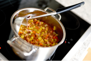 Panela de sopa de frango, cenoura e batata picadas.