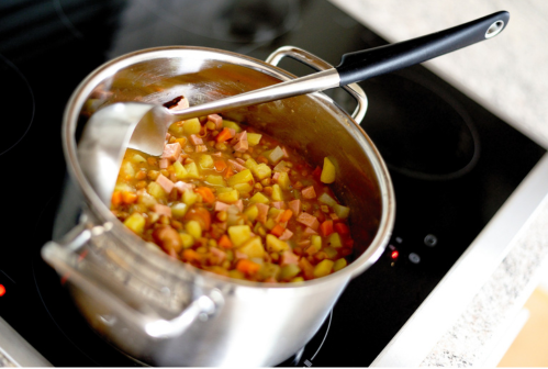 Panela de sopa de frango, cenoura e batata picadas.
