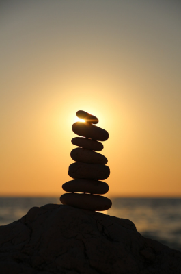 Um pôr do sol dourado ilumina pedras empilhadas em primeiro plano, simbolizando o equilíbrio entre homem e natureza. A luz suave do entardecer cria uma atmosfera de paz, realçando a harmonia da cena.