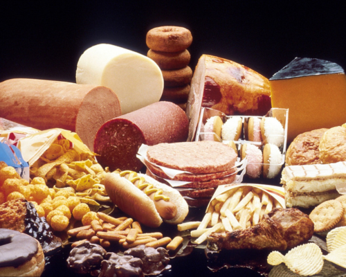 Uma mesa com salames, pães, queijos e outras gordices.